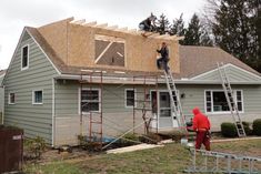 two men working on the roof of a house