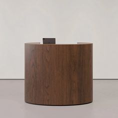 a wooden desk with a metal object on it's top in front of a white wall