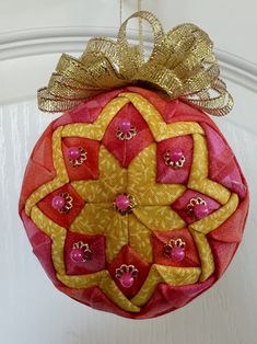 a red ornament hanging from the side of a door with a gold bow