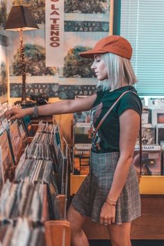 a woman standing in front of a record store shelf with vinyl records on the shelves