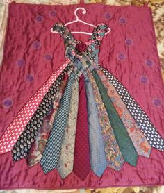 a bunch of ties that are laying on a quilted piece of cloth in the shape of a dress