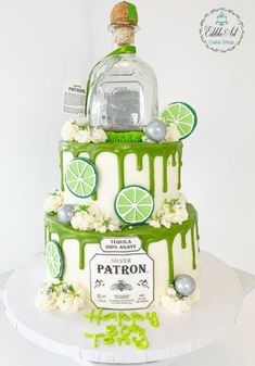 a green and white cake with limes on top is decorated like a bottle of patron