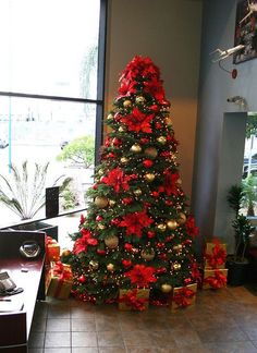 a decorated christmas tree in an office with red and gold ornaments on the bottom half