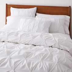 a bed with white sheets and pillows in a room