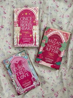 three books laying on top of a bed covered in pink and green covers, one is for children