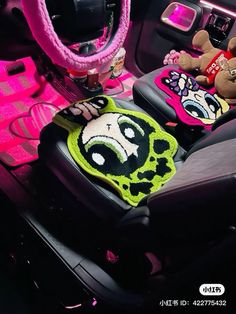 two stuffed animals sit in the center console of a car with pink accessories on it