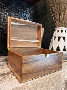 an open wooden box sitting on top of a table next to vases and plants