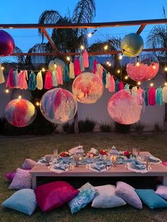 a table is set up for a party with balloons and lights hanging from the ceiling