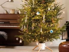 a small christmas tree in a living room next to a piano and coffee table with ornaments on it