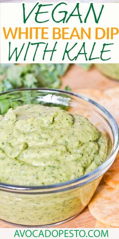 vegan white bean dip with kale in a glass bowl and tortilla chips on the side