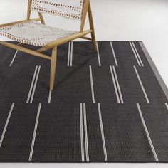 a chair sitting on top of a black rug next to a wooden chair with white stripes