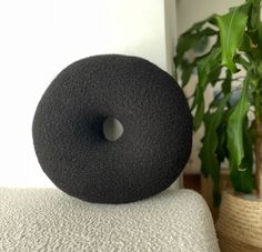 a black donut sitting on top of a white couch next to a potted plant