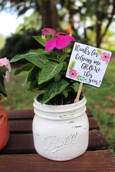 a small potted plant sitting on top of a wooden table next to a sign