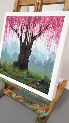 an easel with a painting on it and a pink tree in the foreground