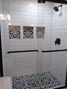 a bathroom with black and white tile on the shower wall, toilet seat cover and hand rail