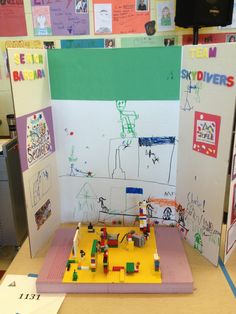 a table with a lego model on it in front of a whiteboard covered wall