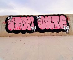 a wall covered in pink graffiti with white bows on the top and bottom letters that spell love