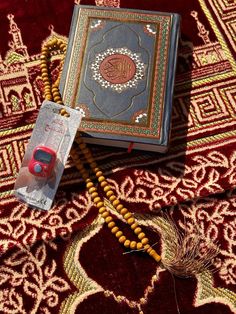 an open book sitting on top of a red rug next to a string of beads