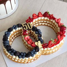 three decorated cookies on top of each other with strawberries, blueberries and raspberries