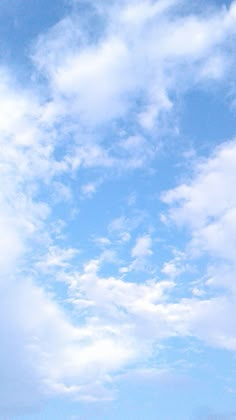 two people standing on the beach flying a kite in the sky with clouds above them