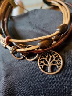 the tree of life bracelet is made from brown leather and has two charms on it