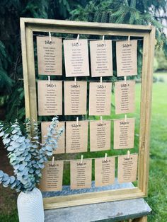 a wooden table with seating cards attached to it and a vase filled with blue flowers