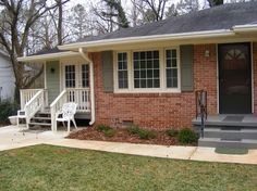 a brick house with steps leading up to the front door and two chairs on the porch