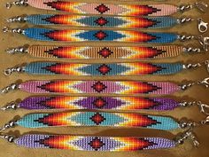 six beaded bracelets are lined up on the floor, each with different colors and designs