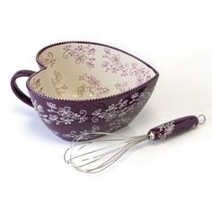 a purple and white bowl with whisk in it next to an egg beater