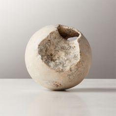 a white vase sitting on top of a table next to a gray wall and floor