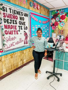 a woman standing in front of a bulletin board with words on it and decorations hanging from the wall behind her