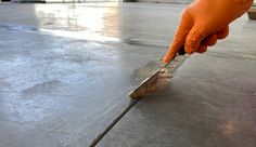 a person in an orange glove is cleaning the floor with a long brush on it