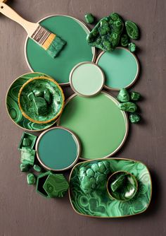 some green paint is sitting on top of plates and bowls with brush in the middle