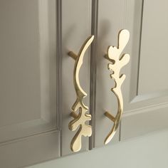 two metal hooks on the side of a white door with gold trim and decorative designs