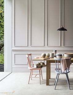 a dining table with two chairs next to an open door that leads into a garden