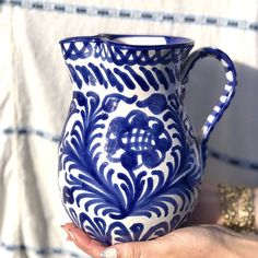 a hand holding a blue and white pitcher