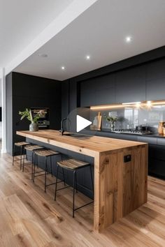 an open kitchen with wooden floors and black cabinets is featured in this modern style home