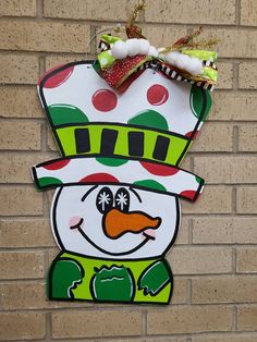 a paper snowman hanging on the side of a brick wall