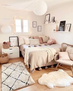 a white bedroom with lots of pillows and blankets on the bed, rugs and other items