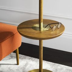 a pair of glasses sitting on top of a wooden table next to an orange chair