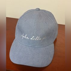 a blue hat with white writing on it sitting on top of a wooden table next to a wall