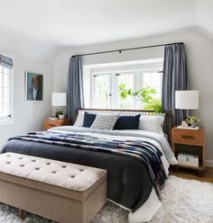 a bedroom with a large bed and white carpeted flooring in front of a window