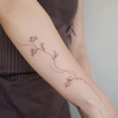 a woman's arm with a vine tattoo on the left side of her arm