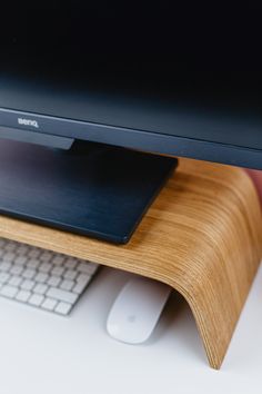 a computer monitor sitting on top of a wooden stand next to a keyboard and mouse