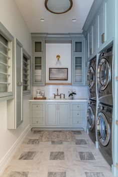 a washer and dryer are in the middle of a laundry room with gray cabinets