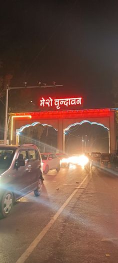 cars are driving down the road at night in front of a sign that reads india