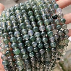 a person is holding some green beads in their hand and it looks like they are made out of glass marbles