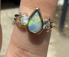 This stunning ring is a true beauty. With a pear-shaped opal as the main stone, it boasts a total of 18k yellow gold and features a bezel setting style. The ring is adorned with two diamonds and one additional gemstone, making it a perfect accessory for any occasion. The multicolor of the stones adds to its charm, and the 18k gold purity ensures its durability. This ring is available in size 6 and is ideal for anyone who loves yellow gold and beauty-themed jewelry. Free shipping! Please feel free to ask any questions Fine Jewelry Opal Ring With Multi-stone Round Cut, 14k Gold Multi-stone Opal Ring, Fine Jewelry Multi-stone Round Cut Opal Ring, 14k Gold Opal Ring With Multi-stone Round Cut, Fine Jewelry Opal Ring With Center Stone, Fine Jewelry Opal Ring With Diamond And Polished Finish, Unique Yellow Gold Opal Ring For Anniversary, Fine Jewelry Pear-shaped Hallmarked Rings, Fine Jewelry 14k Gold Opal Ring With Polished Finish