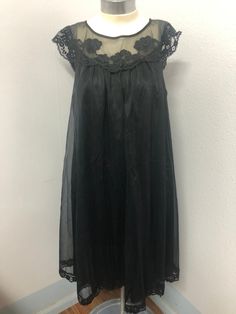 This is a beautiful black nightgown. Label reads Vanity Fair size XS (Extra Small) material is tricot all nylon exclusive of decorations and that the lingerie was made in the USA.  It has tiny flower blossoms along the neckline as decorations.  There is very little wear in the fabric, it's soft and in excellent condition. Black Lace Trim Dress For Night, Sheer Nightgown For Party, Black Lace Dress For Night, Sleeveless Party Nightgown With Delicate Lace, Sheer Lace Nightgown For Party, Sleeveless Lace Nightgown For Party, Sheer Lace Party Nightgown, Sleeveless Lace Party Nightgown, Elegant Black Nightgown For Summer