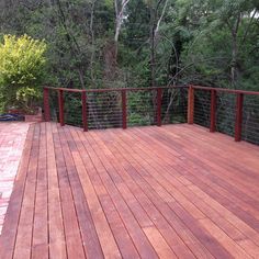 a wooden deck with metal railings and trees in the background